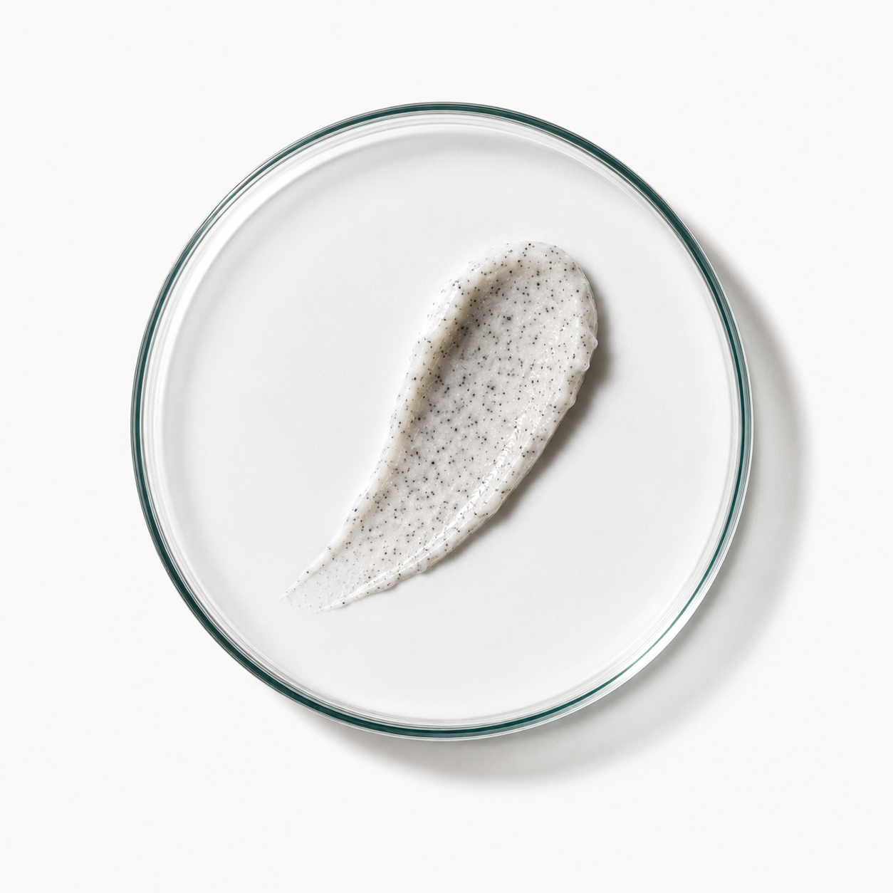 White scalp scrub with specks on a clear glass plate against a white background